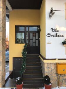a yellow building with a black door and stairs at Apartments Villa Svetlana in Vrnjačka Banja