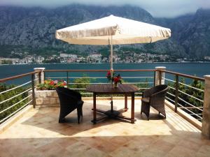 a table and chairs with an umbrella on a balcony at Villa "M Family" in Kotor