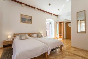 a white bedroom with a large bed and a window at Carrara Accommodation in Split