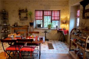 uma sala de jantar com mesa, cadeiras e janelas em Demeure d'Hôtes L'Hermitage em Mouxy