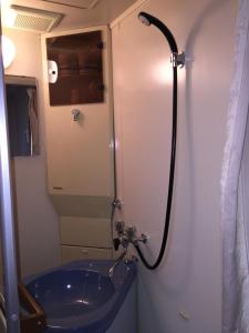 ein Badezimmer mit einer Dusche und einer blauen Badewanne in der Unterkunft Pension Old String in Minakami