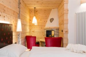 a bedroom with a bed and two red chairs at Wellness Hotel Lupo Bianco in Canazei