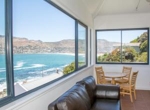 a room with a table and chairs and a view of the ocean at Modern Beach Apartment in Kalk Bay