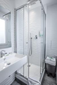 a white bathroom with a shower and a sink at Prince Albert Wagram in Paris