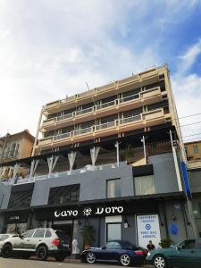 un gran edificio con coches estacionados frente a él en Cavo D' Oro, en Pireo