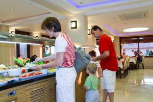 a woman and a man and a child preparing food at a buffet at Perdikia Hill Hotel And Villas in Oludeniz