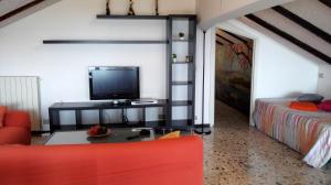 een woonkamer met een tv en een rode bank bij Lucrezia Garden Catania in San Gregorio di Catania