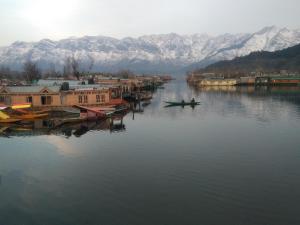 two people in a boat on a river with mountains at SnowGoose Group of Houseboats in Srinagar