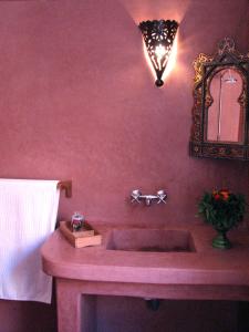 a pink bathroom with a sink and a mirror at Maison Xanadu in Sidi Ifni