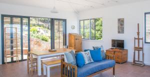 a living room with a table and a blue couch at Modern Beach Apartment in Kalk Bay