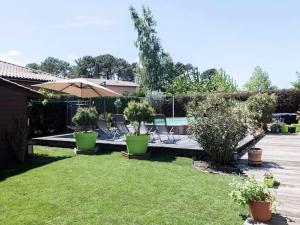 un patio con sillas, una sombrilla y una piscina en Calme et Nature, BA, en Gujan-Mestras