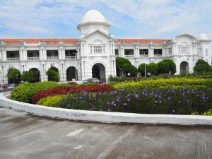 a large building with a flower garden in front of it at Brick Box Hotel @ Oldtown Ipoh in Ipoh
