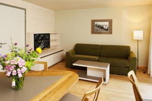 a living room with a couch and a table with flowers at Familienhotel Weimar mit Ferienwohnungen in Weimar