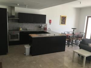 a kitchen with black cabinets and a living room at Apartment in Jebel Sifah in As Sīfah