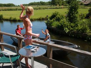 a girl is standing on a railing on a boat at Hotel de Harmonie in Giethoorn