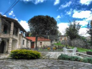 a stone house with two white chairs in a yard at Rodami in Kaléntzion