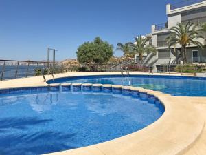 a large swimming pool with chairs and a building at Seaside Villa in Alicante