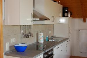 a kitchen with white cabinets and a blue bowl on the counter at Ferienwohnung Brock in Breitenbrunn