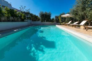 piscina con acqua blu e sedie a sdraio di La Casèdde a Cisternino