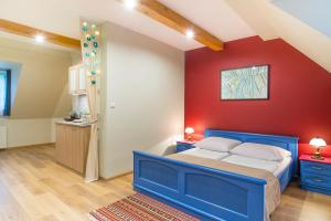 a bedroom with a blue bed and a red wall at Dom Góreckich in Kazimierz Dolny
