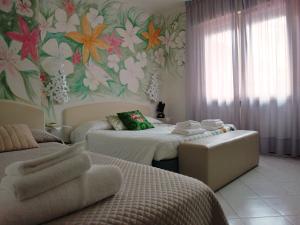 1 dormitorio con 2 camas y papel pintado con motivos florales en Hotel Julia en Lido degli Estensi