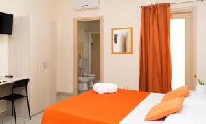 a bedroom with a bed and a desk and a bathroom at B&B Alta Marea Pozzallo in Pozzallo