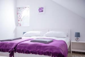 a white bedroom with a purple blanket on a bed at Baltic Stone in Rewal