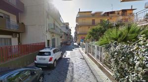 a white car parked on a street with buildings at B&B San Martino in Misterbianco