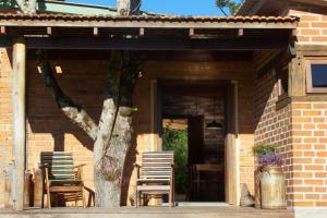 een stenen huis met stoelen en een tafel en een boom bij Loft no campo próximo ao Vale dos Vinhedos in Garibaldi