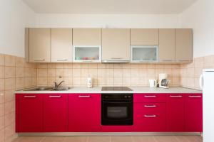 kuchnia z czerwonymi szafkami i czarną zmywarką do naczyń w obiekcie Apartment Nevenka w Krku