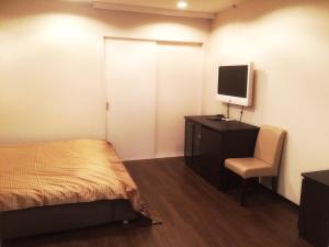 a bedroom with a bed and a desk with a television at Hotel Maganda (Adult Only) in Osaka