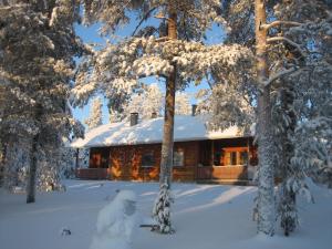 a snow man standing in front of a log cabin at Kieppi Chalet in Rovaniemi