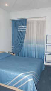 a bedroom with a blue bed and blue curtains at Hotel Olimp in Vyalki