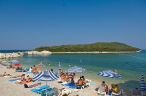 a group of people on a beach with umbrellas at Degrassi Square Apartments in Vrsar