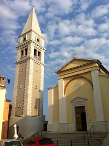 a church with a clock tower next to a building at Degrassi Square Apartments in Vrsar