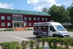 a van parked in a parking lot in front of a red building at Hotel Olimp in Vyalki