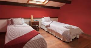 two beds in a room with red walls at La Estibialla in Campo