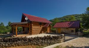 a log cabin with a red roof and a stone wall at Country House Doliba in Mušaluk