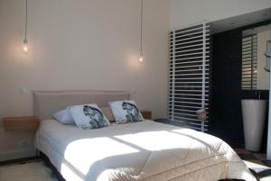 a bedroom with a white bed with two pillows at Appartement Du Fau De La Roque in Villefranche-de-Rouergue