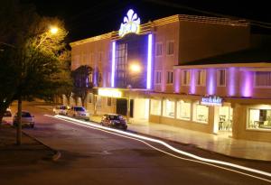 un bâtiment avec des lumières violettes sur une rue la nuit dans l'établissement Hotel Casino Hue Melen, à Zapala