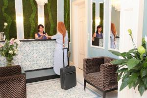 a woman with red hair standing at a counter with a suitcase at Ferdinandhof Apart-Hotel in Karlovy Vary