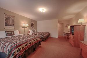 a hotel room with two beds and a desk at City Center Motel in West Yellowstone