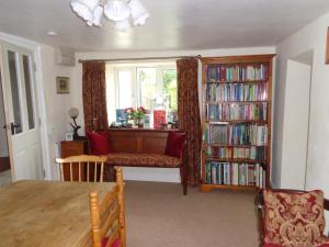 un soggiorno con finestra e una libreria piena di libri. di Lodge House B&B a Buckland St Mary