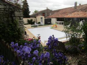 um jardim com piscina e flores roxas em La Piaule em Saint-Pierre-le-Vieux