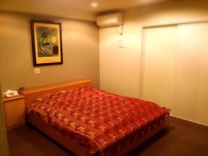 a bedroom with a bed with a red comforter at Hotel Maganda (Adult Only) in Osaka