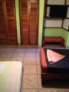 a room with two beds and a television and wooden doors at La Casa de Rolando in Puerto Viejo