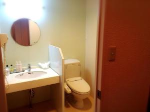 a bathroom with a toilet and a sink and a mirror at Hotel Maganda (Adult Only) in Osaka