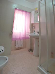 Fossato di VicoにあるAppartamento Bellavistaのピンクのシャワーカーテンとシンク付きのバスルーム