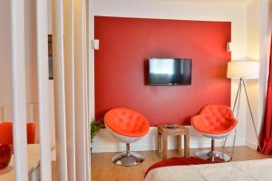 トゥールーズにあるStudio rouge Ramblas Centre Toulouseの赤い壁にテレビとオレンジの椅子2脚が備わる客室です。