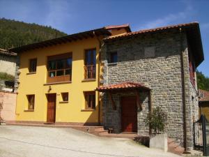 un edificio amarillo con una puerta en la parte delantera en El Mirador de Valdedios " Casa Friera", en Puelles